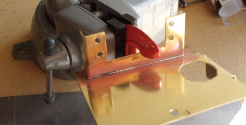 Brass sheet in a vice grip getting prepped for soldering